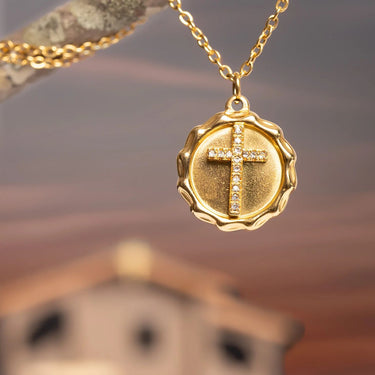 Gold necklace with a cross pendant against a blurred background