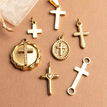 Collection of gold cross pendants on a beige background
