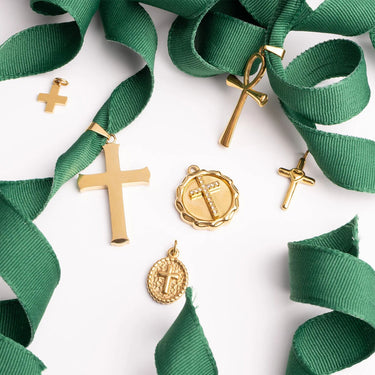 Gold religious charms with green ribbons on a white background