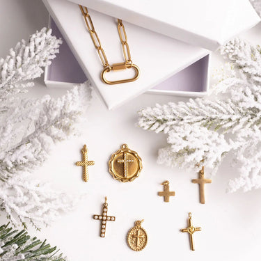 Gold jewelry pendants on a white surface with decorative branches