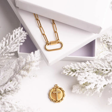 Gold necklace and pendant on a white surface with decorative elements