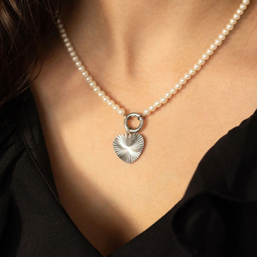 Pearl necklace with a silver heart pendant worn by a person