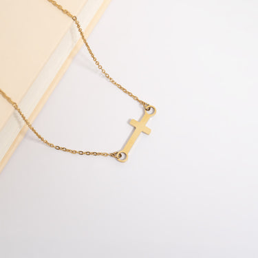 Gold necklace with a cross pendant on a light background