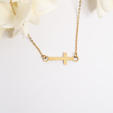 Gold cross necklace on a white background