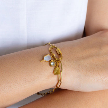 Gold bracelet with charms on a wrist against a white background