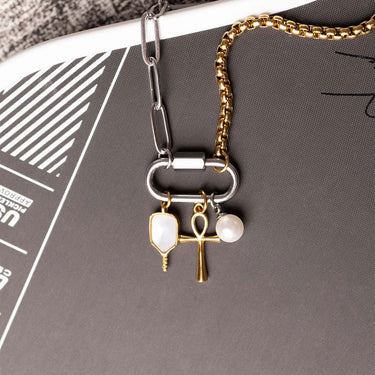 Necklace with key and ankh charms on a gray surface