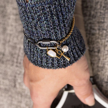Close-up of a hand wearing a dark blue knit sleeve with a keychain featuring a key and heart charm.