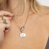 Person wearing a silver necklace with a camera pendant