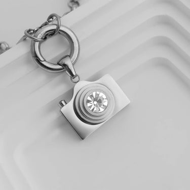 Silver keychain with a camera-shaped pendant on a light gray background