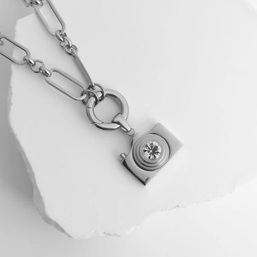 Silver chain bracelet with a diamond charm on a white stone surface