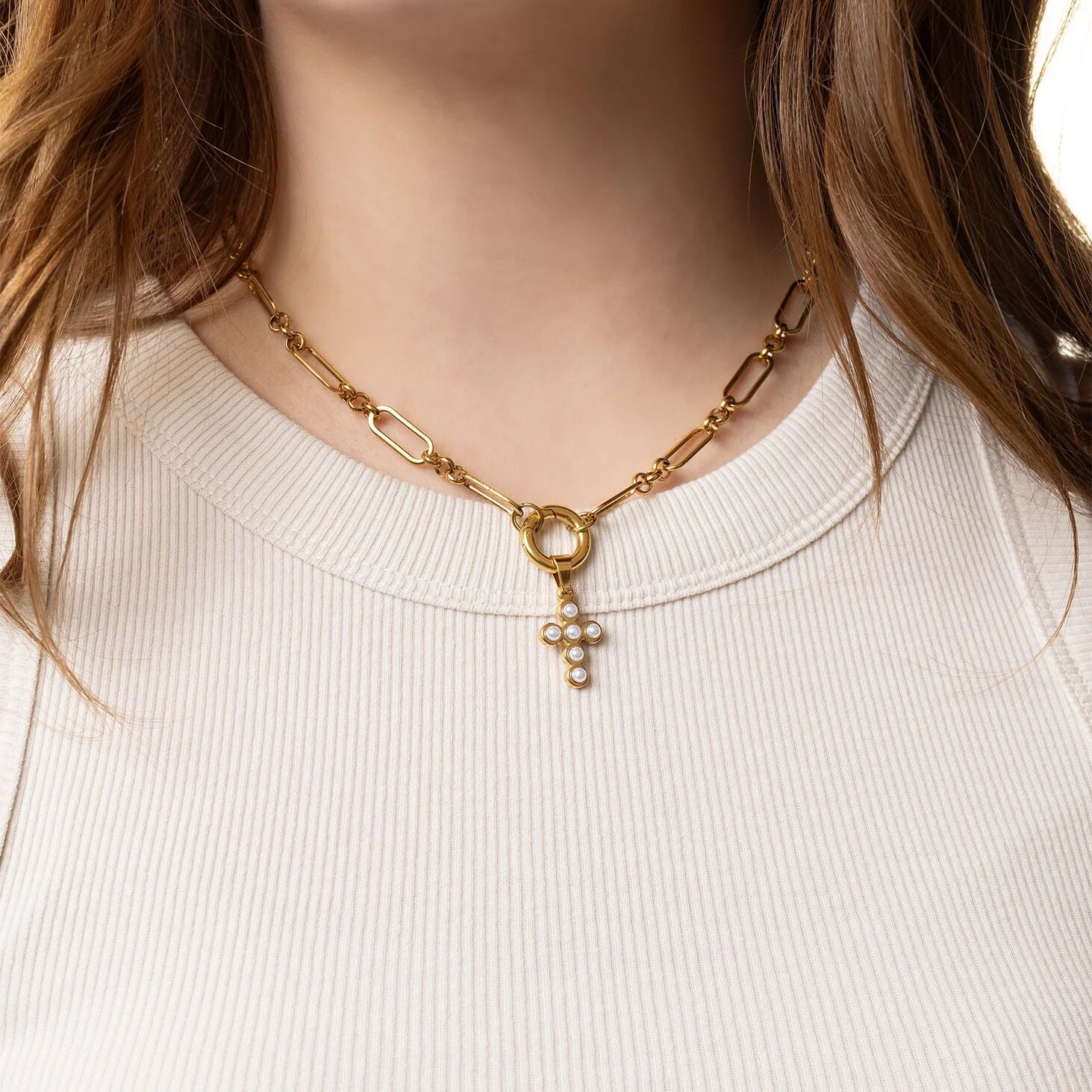 Gold chain necklace with a pendant worn by a person against a white background