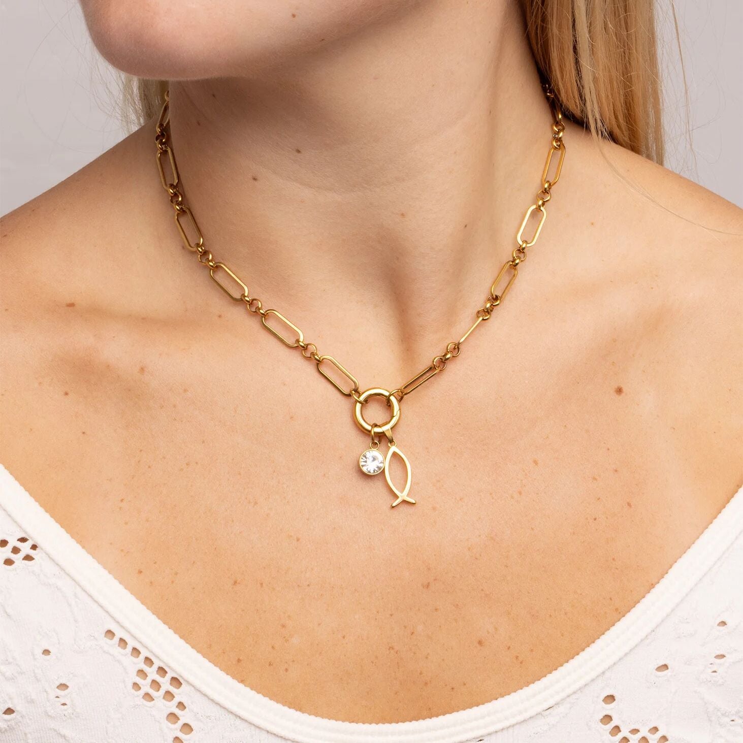 Gold necklace with a pendant on a person wearing a white top