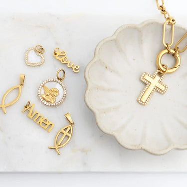 Collection of gold pendants on a white dish with a marble background