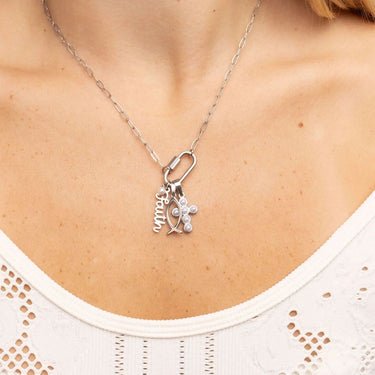 Silver necklace with charms on a person wearing a white top