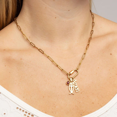 Gold necklace with a fish charm and red gemstone on a person wearing a white top.