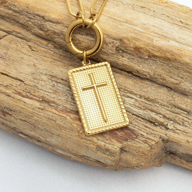 Gold pendant with cross design on a wooden surface