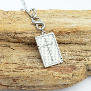 Silver cross pendant on a wooden surface