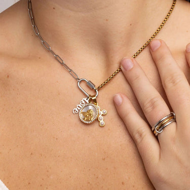 Necklace with a pendant worn by a person, hand visible wearing a ring.