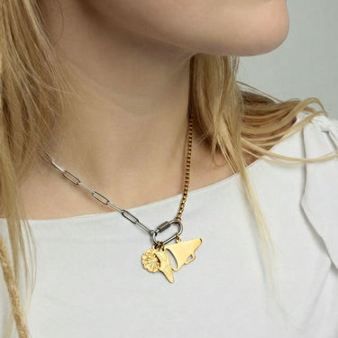 Gold necklace with a unique pendant worn by a person against a neutral background