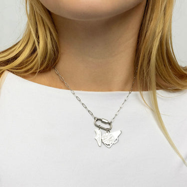 Silver butterfly necklace on a person wearing a white top