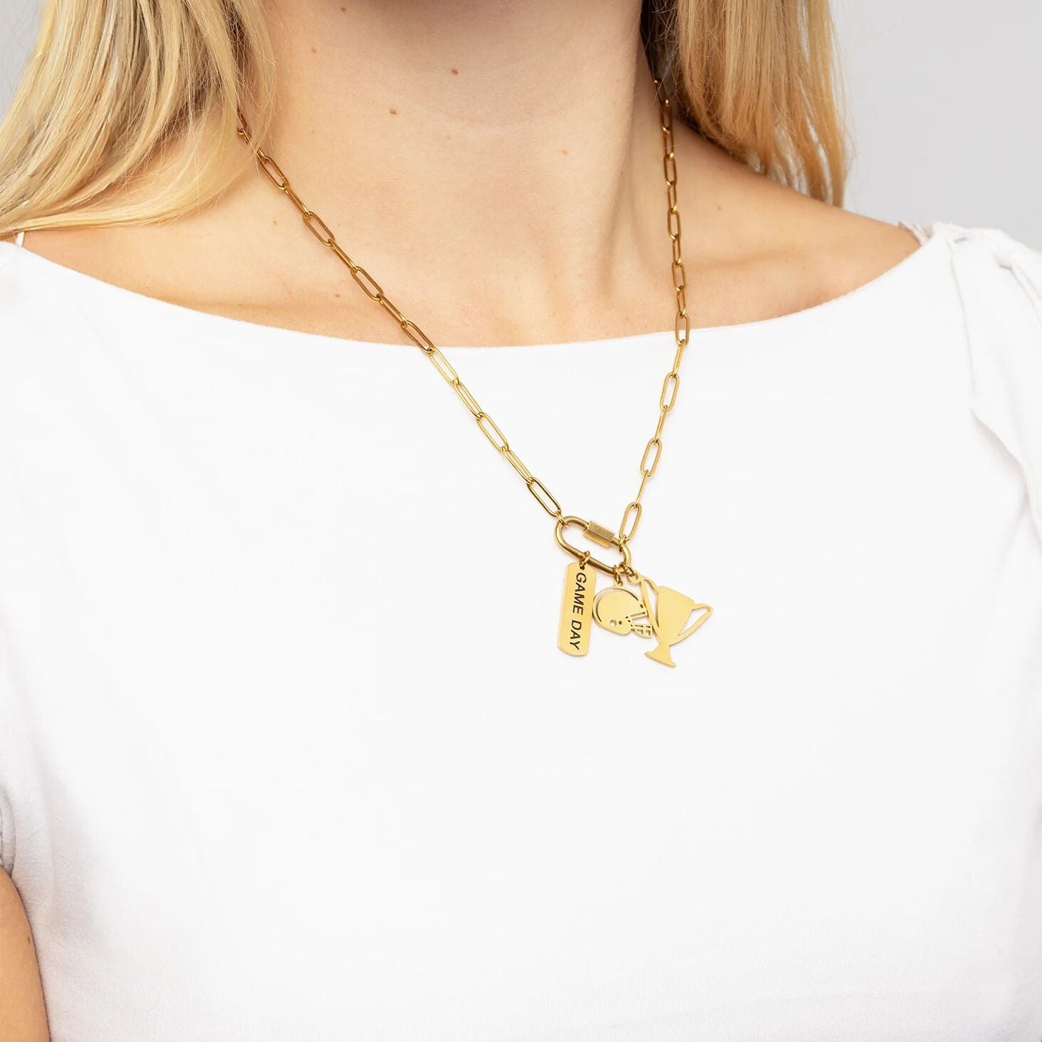 Gold necklace with charms worn by a person on a white background