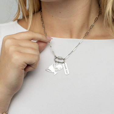 Person wearing a silver necklace with charms on a plain background