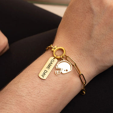 Gold bracelet with 'GAME DAY' tag and football helmet charm on wrist