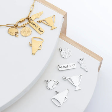 Collection of gold and silver charms on a white surface with a wooden frame.