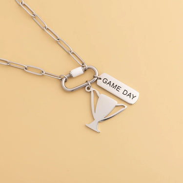 Silver necklace with 'GAME DAY' pendant on a beige background