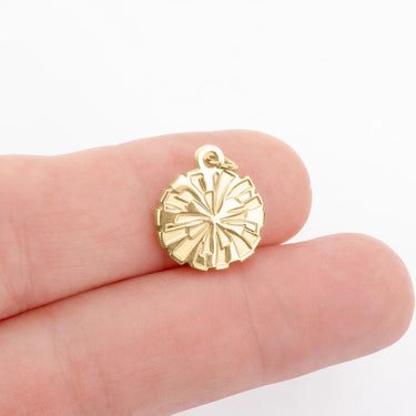 Gold compass pendant held between fingers on a white background