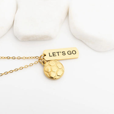 Gold necklace with 'LET'S GO' tag and soccer ball pendant on a white background