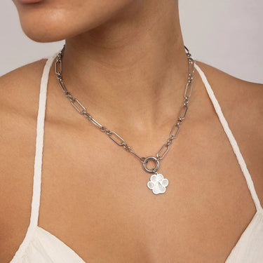 Silver chain necklace with a paw print pendant worn by a person.