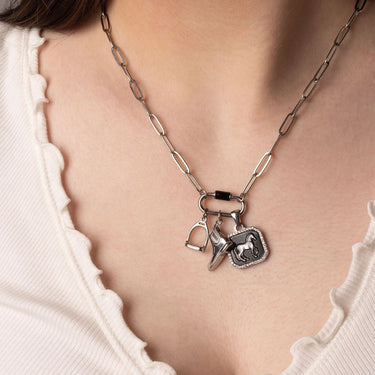Silver necklace with horse, stirrup and boot charms on a white background