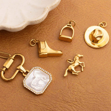Collection of gold jewelry charms on a brown surface