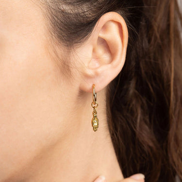 Gold earring worn by a person with dark hair.