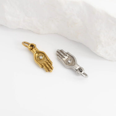 Gold and silver hand-shaped charms on a white fabric background