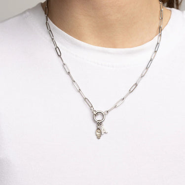 Silver chain necklace with a small pendant on a white shirt