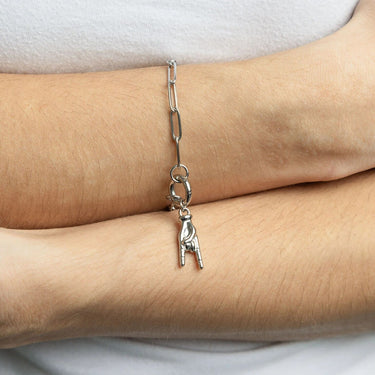 Silver chain bracelet with a small charm on a wrist against a white background