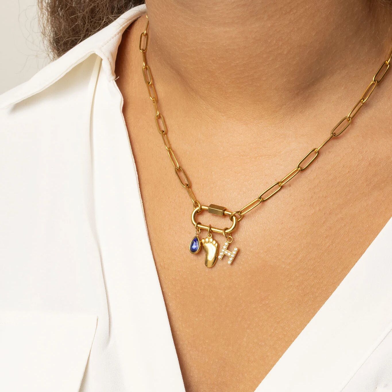 Gold necklace with Baby Foot Charm on a person wearing a white shirt