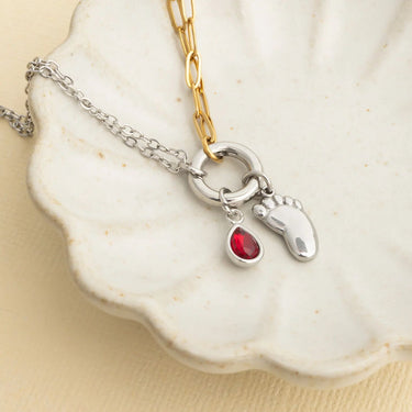 Necklace with a red gemstone and Baby Foot Charm on a shell background