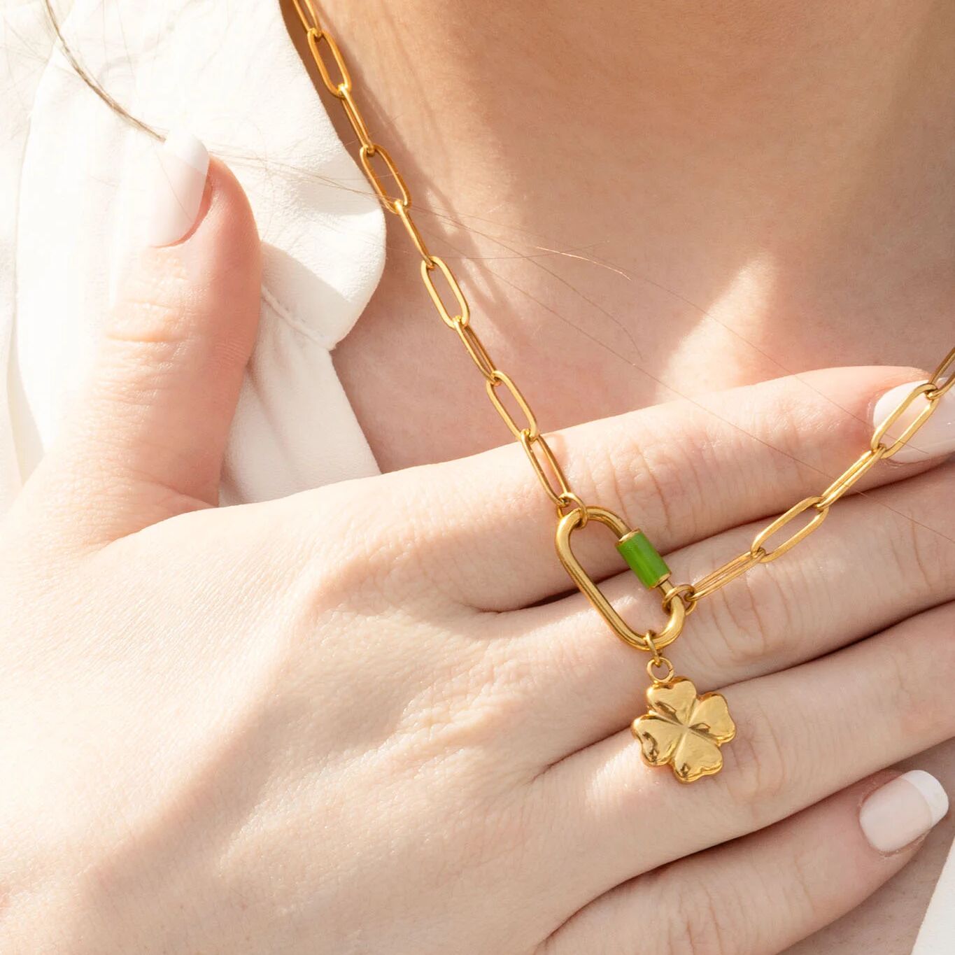 Gold chain necklace with a clover charm on a hand