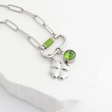 Silver necklace with shamrock charm and green gemstone on a white background