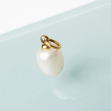 Pearl charm on a gold chain against a light blue background