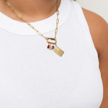 Gold necklace with Flag Charm and red, clear and blue teardrop birthstone charms on a white background