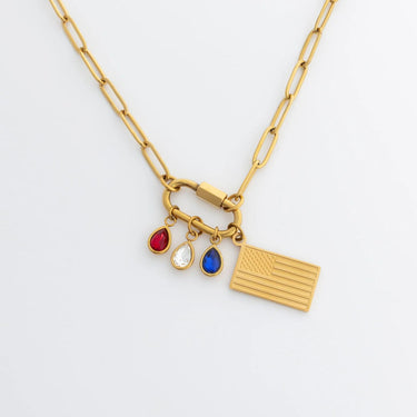 Gold necklace with Flag Charm and red, clear and blue teardrop birthstone charms on a white background