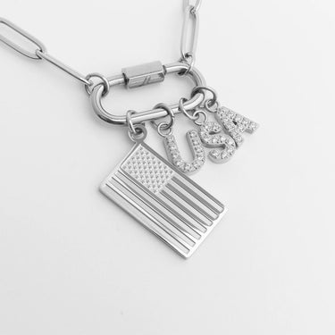 Silver necklace with American flag and 'USA' charm on a light gray background
