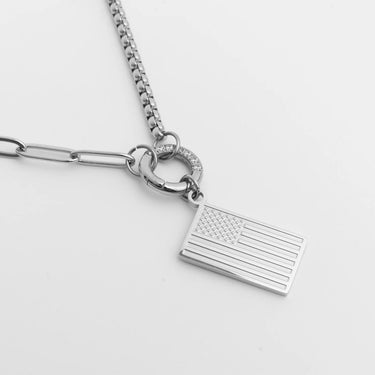 Silver necklace with an American flag pendant on a light gray background