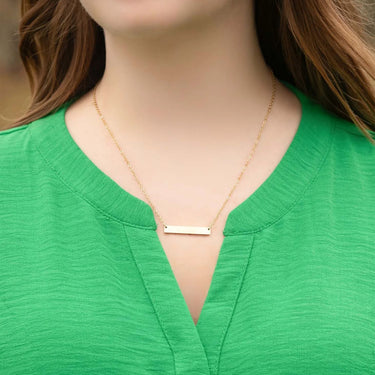 Gold necklace on a person wearing a green top