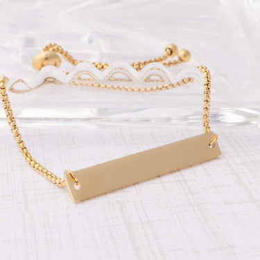 Gold bar necklace on a white lace background