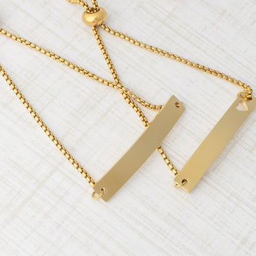Gold necklace with bar pendants on a textured white background